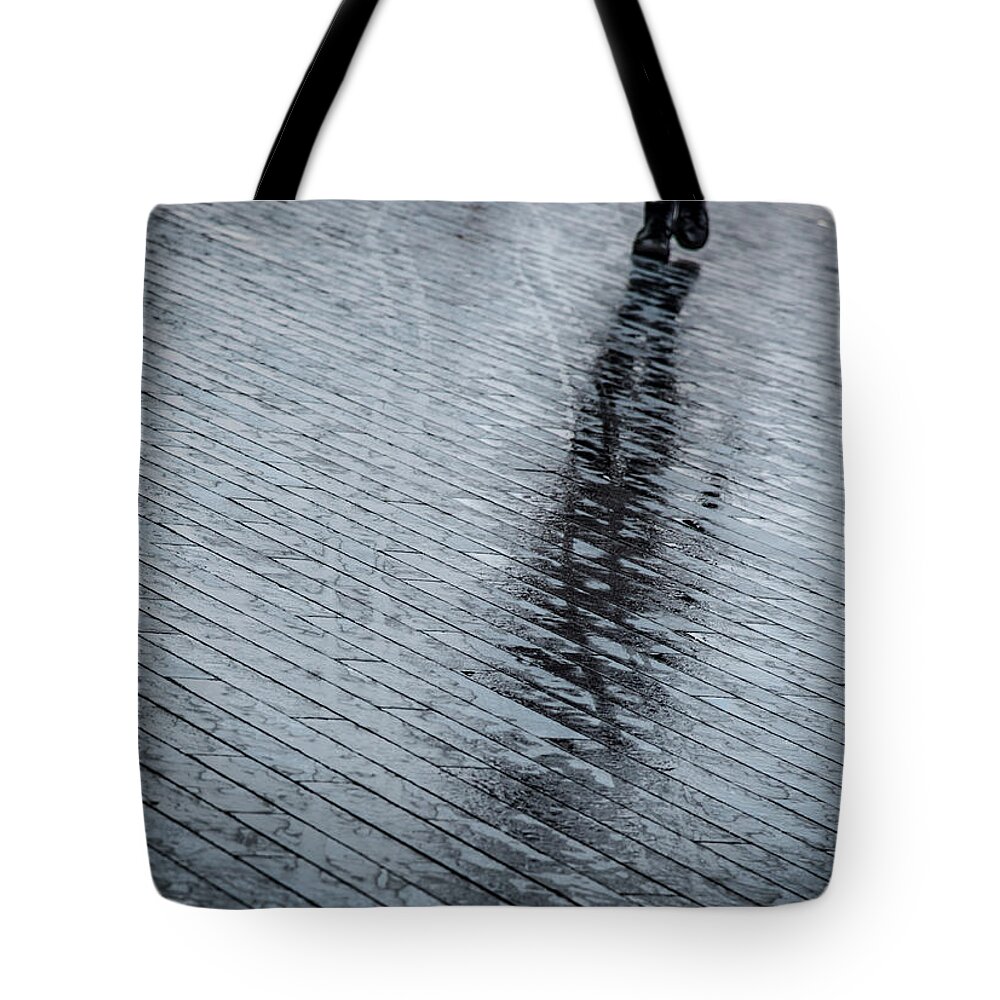 Silhouette Tote Bag featuring the photograph Walking shadow of an unrecognised person walking on wet streets by Michalakis Ppalis