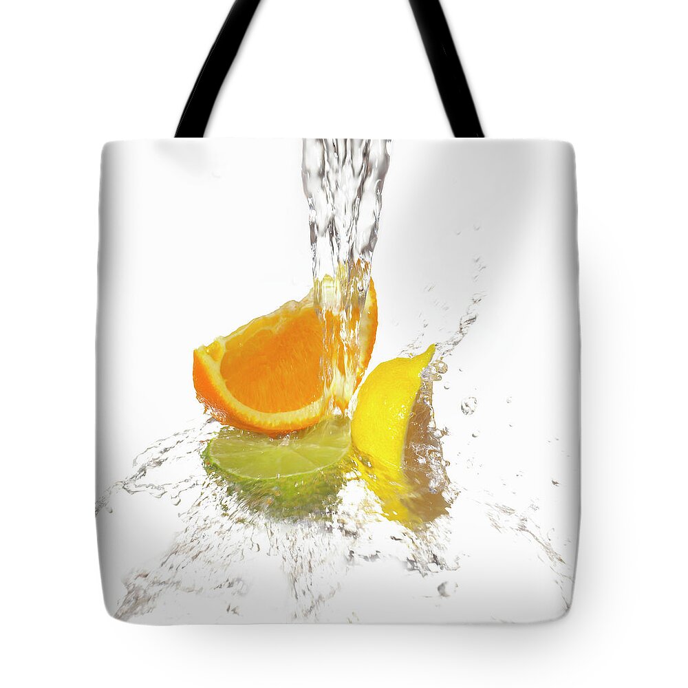 White Background Tote Bag featuring the photograph Water Splashing On Citrus Slices by Annabelle Breakey