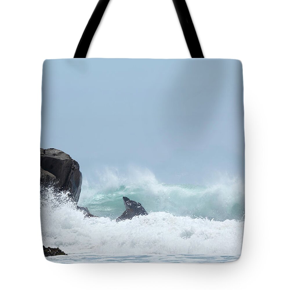 Water's Edge Tote Bag featuring the photograph Wave Smashing Aginst Black Rocks In by Arturbo
