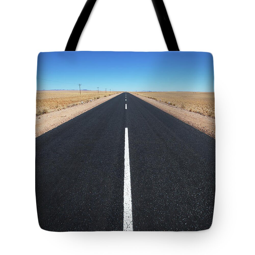 Namibia Tote Bag featuring the photograph White Line On A Paved Road In The Desert by Lars Froelich / Design Pics
