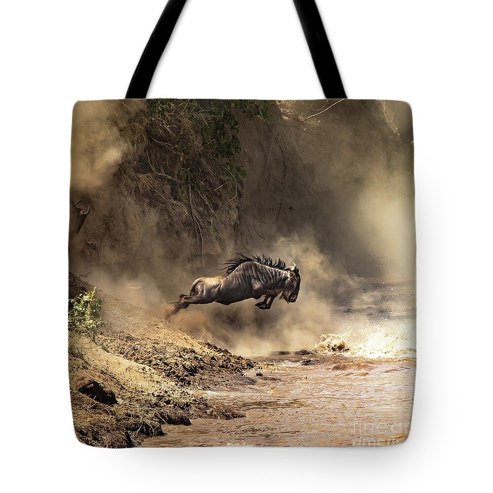 Mara Tote Bag featuring the photograph Wildebeest leaps from the bank of the Mara river by Jane Rix