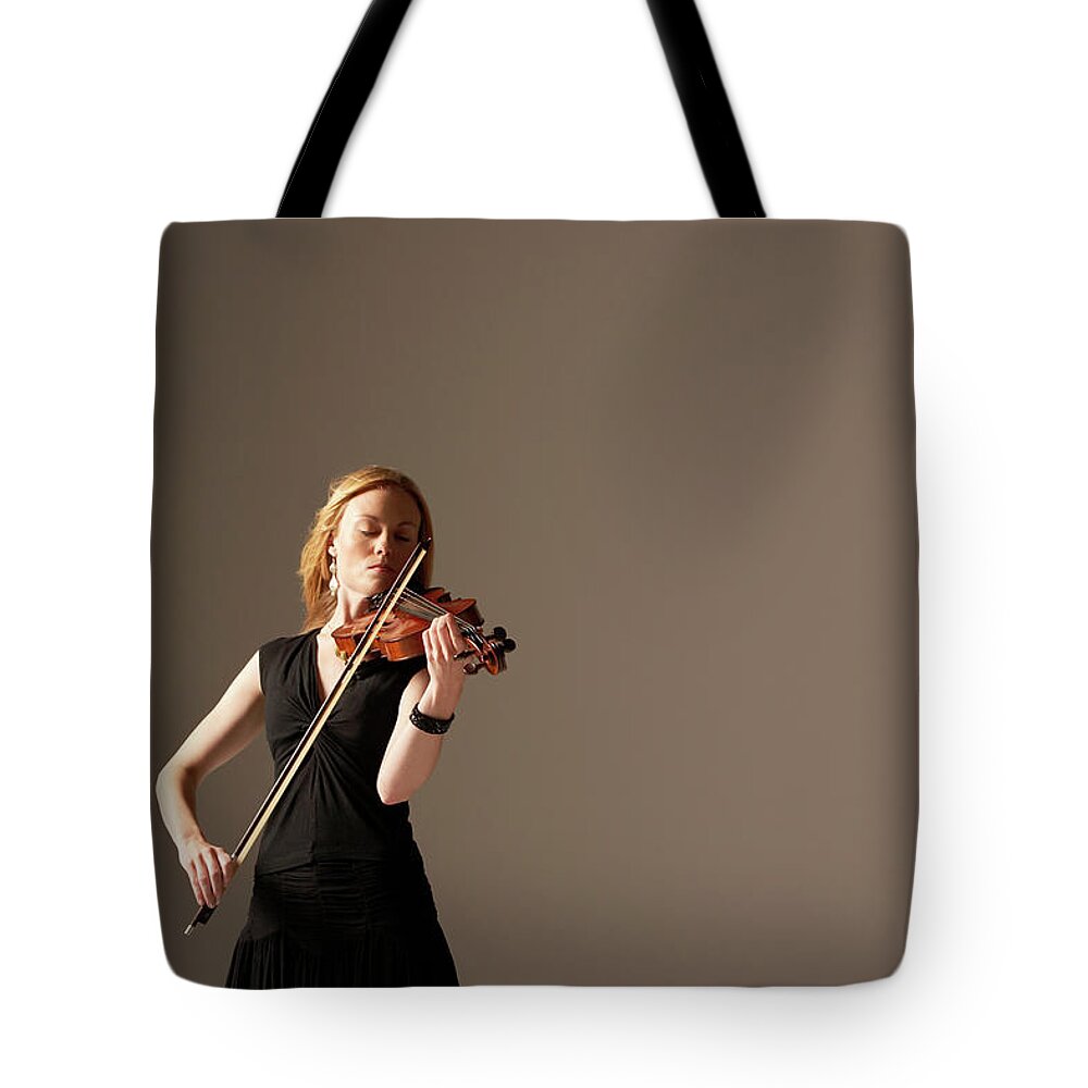 Mid Adult Women Tote Bag featuring the photograph Woman Playing Violin by Moodboard