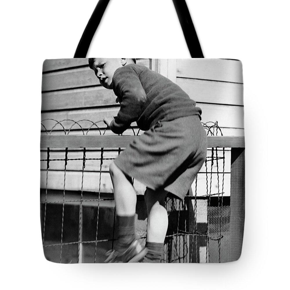 Child Tote Bag featuring the photograph Young Boy Climbing Fence by George Marks