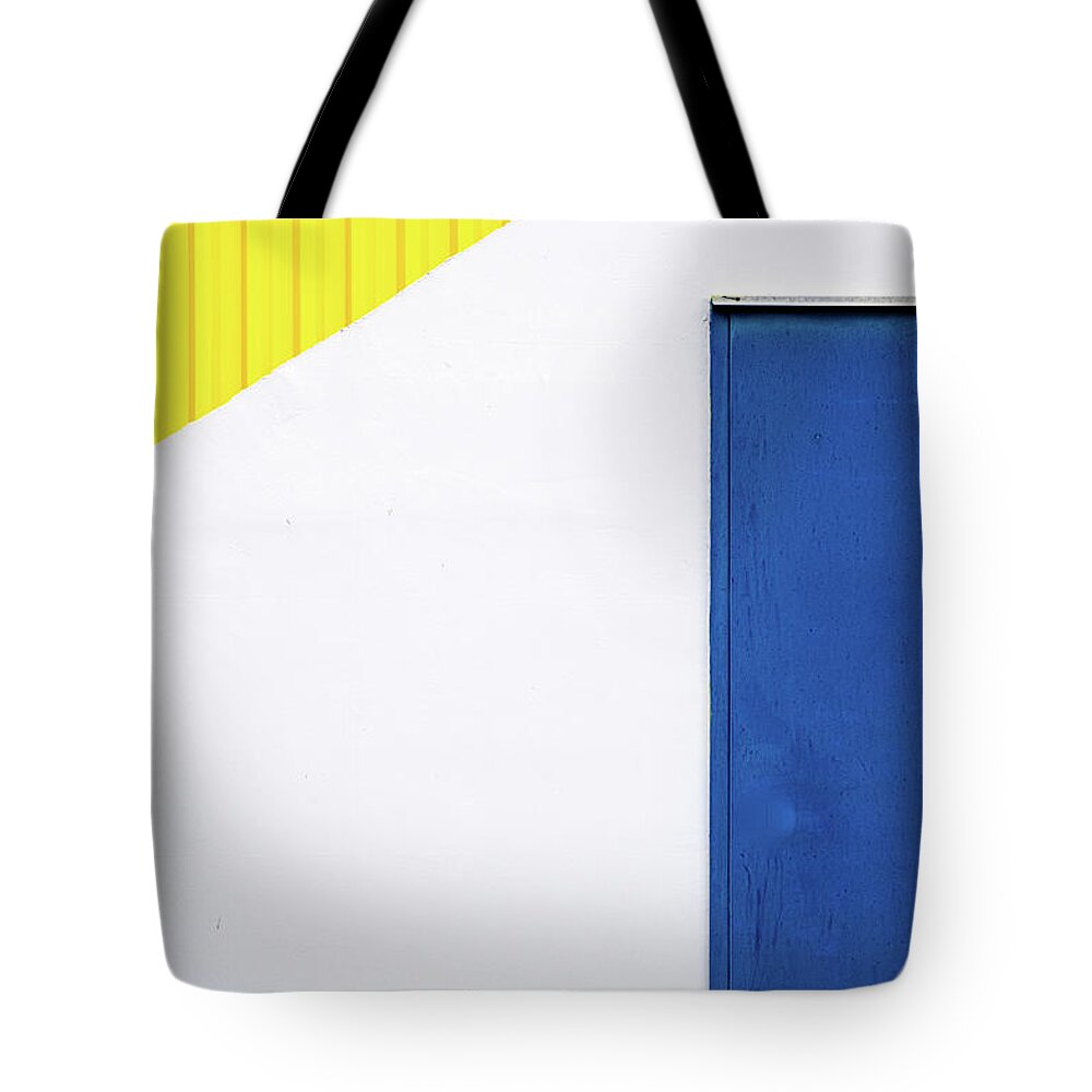 Minimal Tote Bag featuring the photograph Blue close metal door on a white and yellow wall. #1 by Michalakis Ppalis