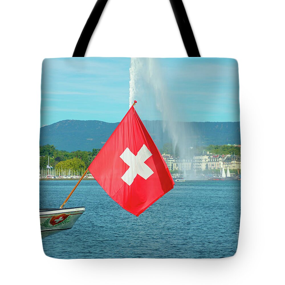 Geneva Tote Bag featuring the photograph Water jet fountain and Swiss flag #1 by Benny Marty