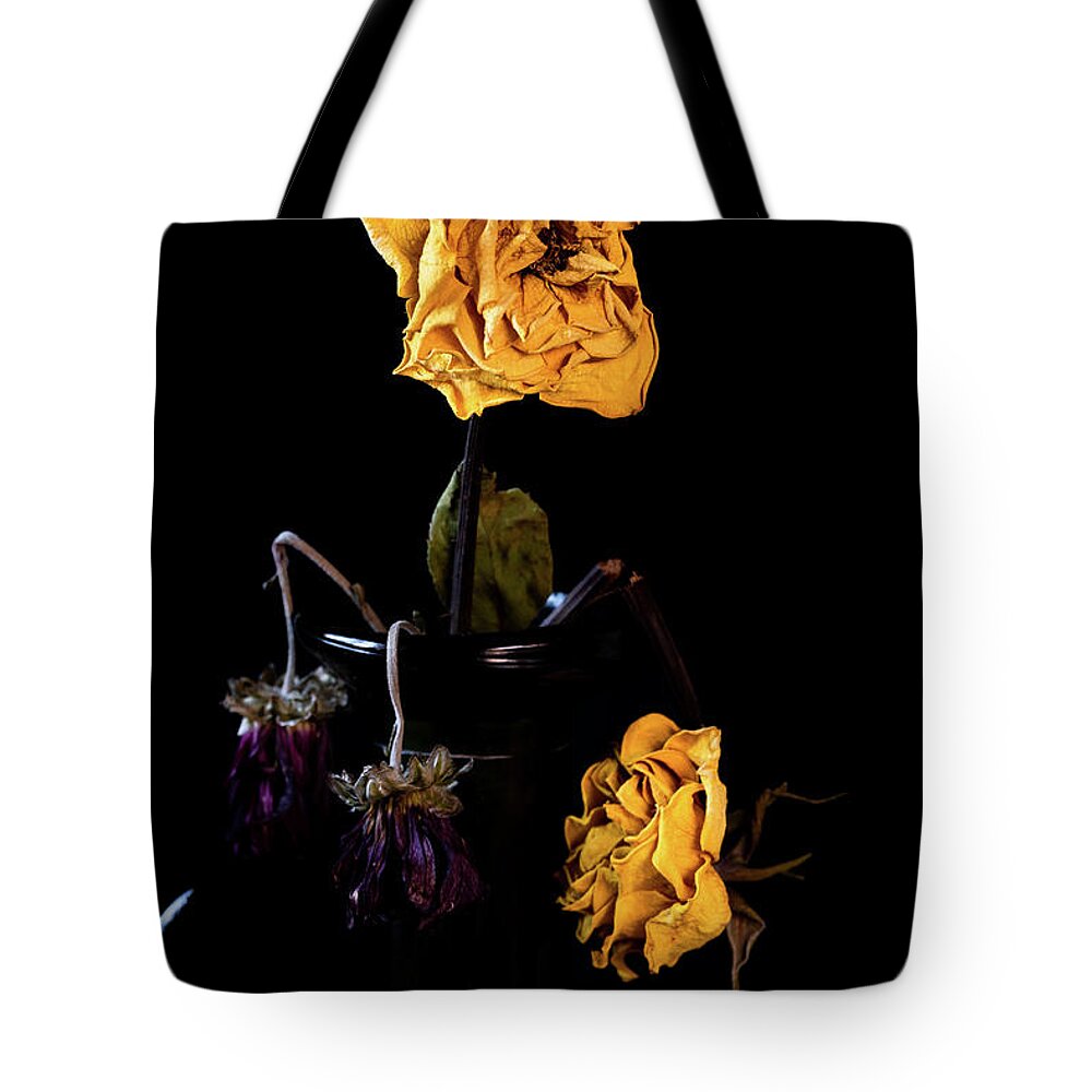 Wither Tote Bag featuring the photograph Wilted and dry yellow rose flower on a vase on a black background. by Michalakis Ppalis