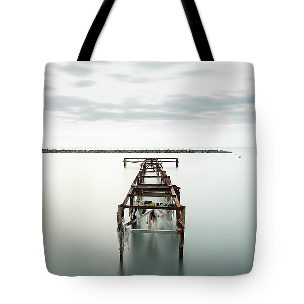 Jetty Tote Bag featuring the photograph Abandoned pier in the ocean. Long Exposure by Michalakis Ppalis
