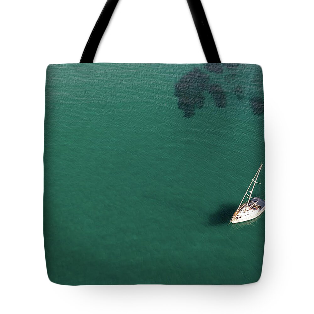 Anchored Tote Bag featuring the photograph Aerial view of a luxury yacht anchored in the surface of the sea. Cyprus vacations by Michalakis Ppalis