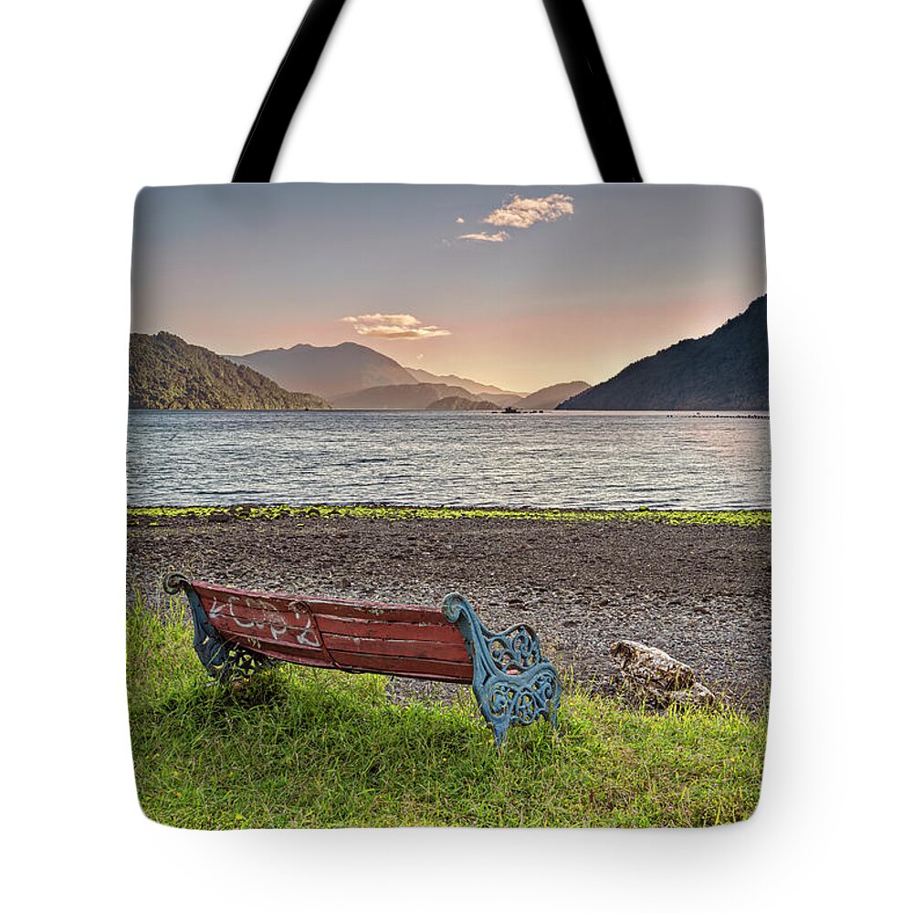 Chili Tote Bag featuring the photograph Bench with a peacefull view on the Hornopiren fjord on sunset by Henri Leduc