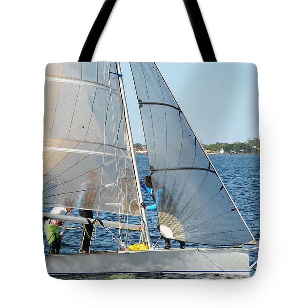 Sky Tote Bag featuring the photograph Children Sailing small dinghy with white sails up-close on an in by Geoff Childs