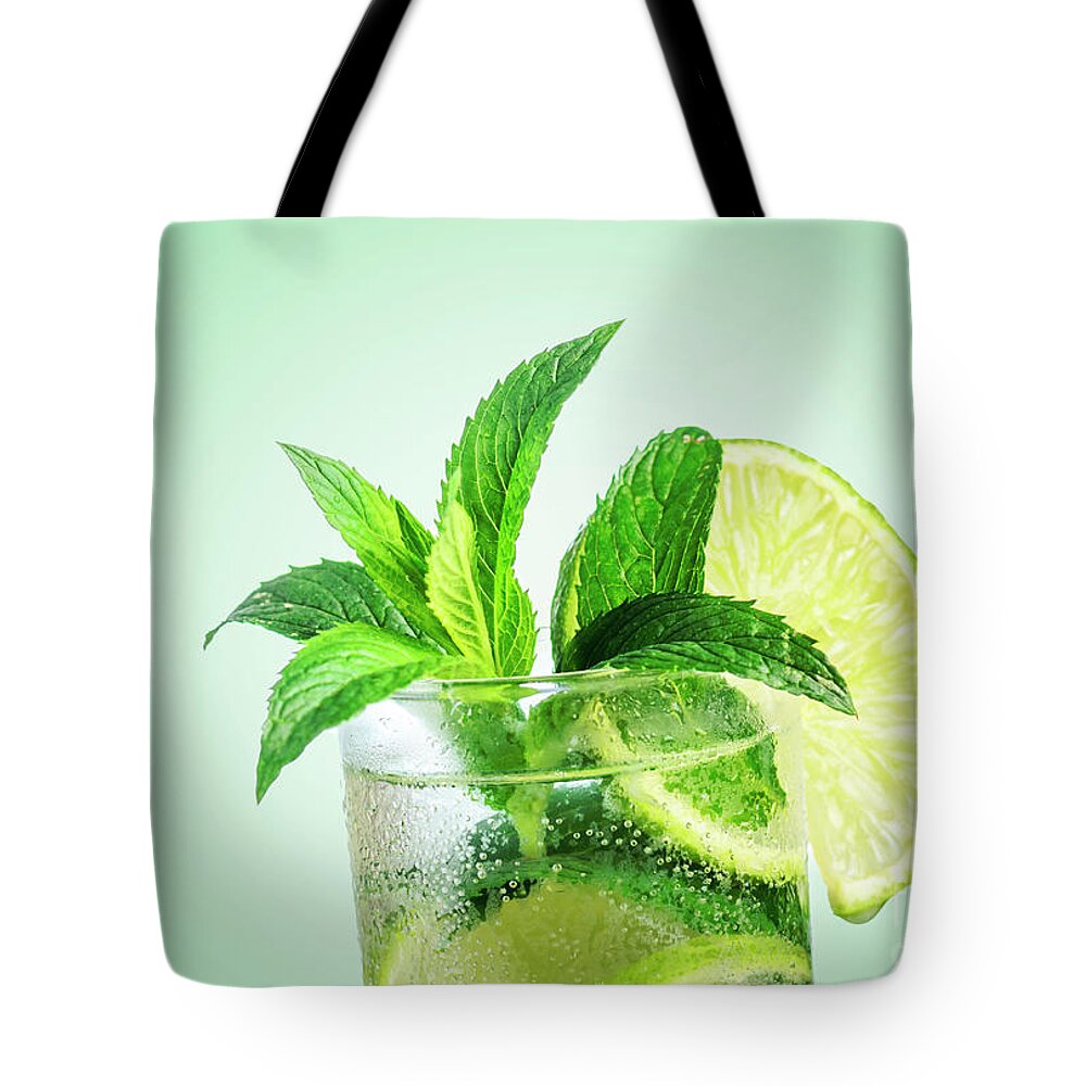 Mojito Tote Bag featuring the photograph Closeup mojito cocktail with ice isolated over pastel background by Jelena Jovanovic