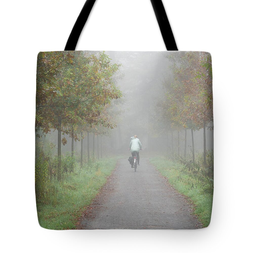 Cyclist Tote Bag featuring the photograph Cyclist in the mist by Anges Van der Logt