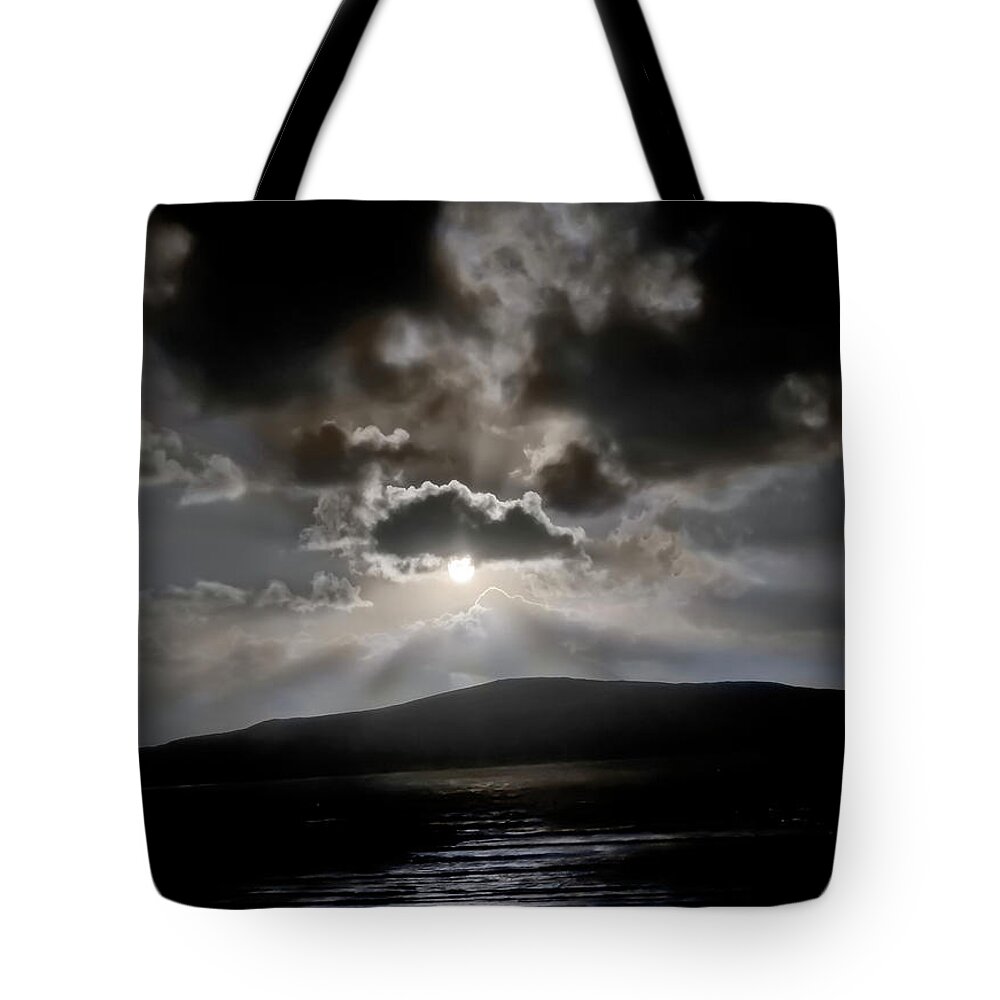 Dramatic Sunset Saeilebost Harris Scotland Highlands Sun Rays Heavy Clouds Sea Mountains Setting Sky Reflections Landscape Beautiful Breathtaking Magnificent Spectacular Exceptional Singular Remarkable Delightful Mindfulness Artistic Serenity Inspirational Serene Stylish Magic Poetic Striking Charming Atmospheric Aesthetic Attractive Glorious Impressions Impressionistic Impressive Stunning Fabulous Thrilling Stimulating Mind-blowing Fantastic Awesome Painterly Dark Black Stormy Sunrise Dawn Dusk Tote Bag featuring the photograph Dramatic sunset, Seilebost, WEST HARRIS, SCOTLAND by Tatiana Bogracheva