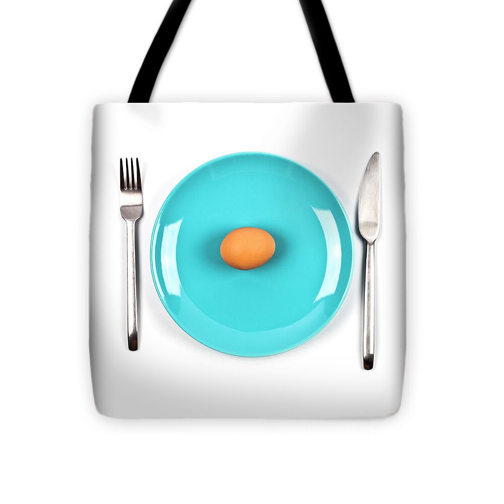 Fresh chicken boiled egg on blue plate, fork and knife on white Tote Bag