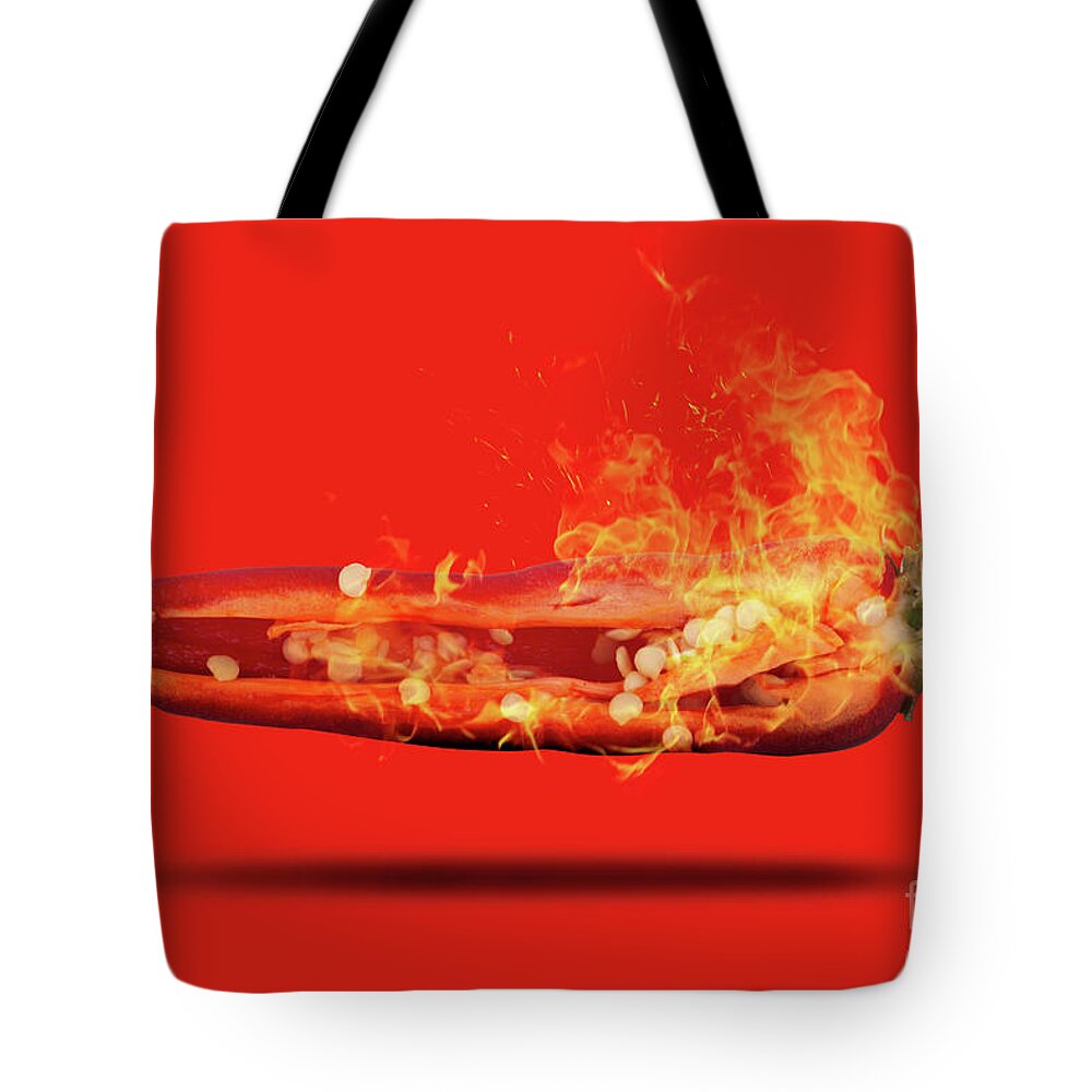 Red Tote Bag featuring the photograph Half a red chili pepper on fire with seeds by Simon Bratt