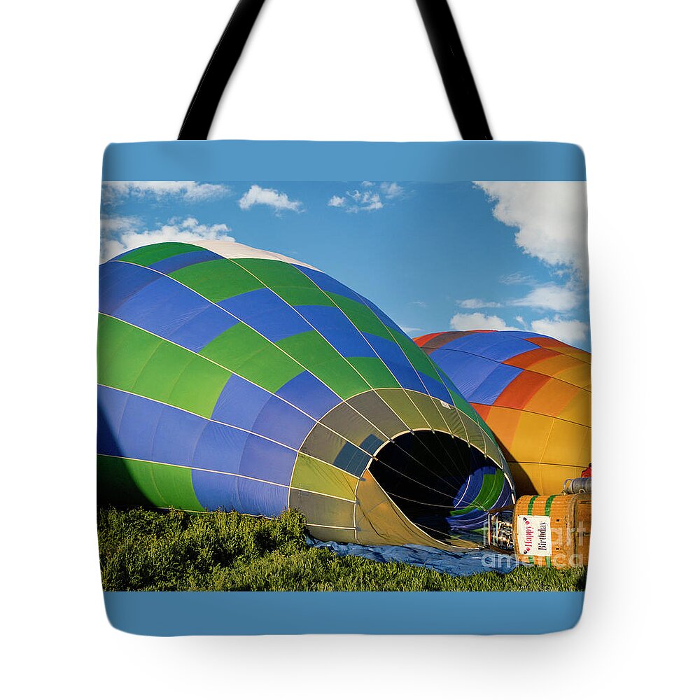Balloon Tote Bag featuring the photograph Hot air balloons filling up with hot air and getting ready to take off. by Gunther Allen
