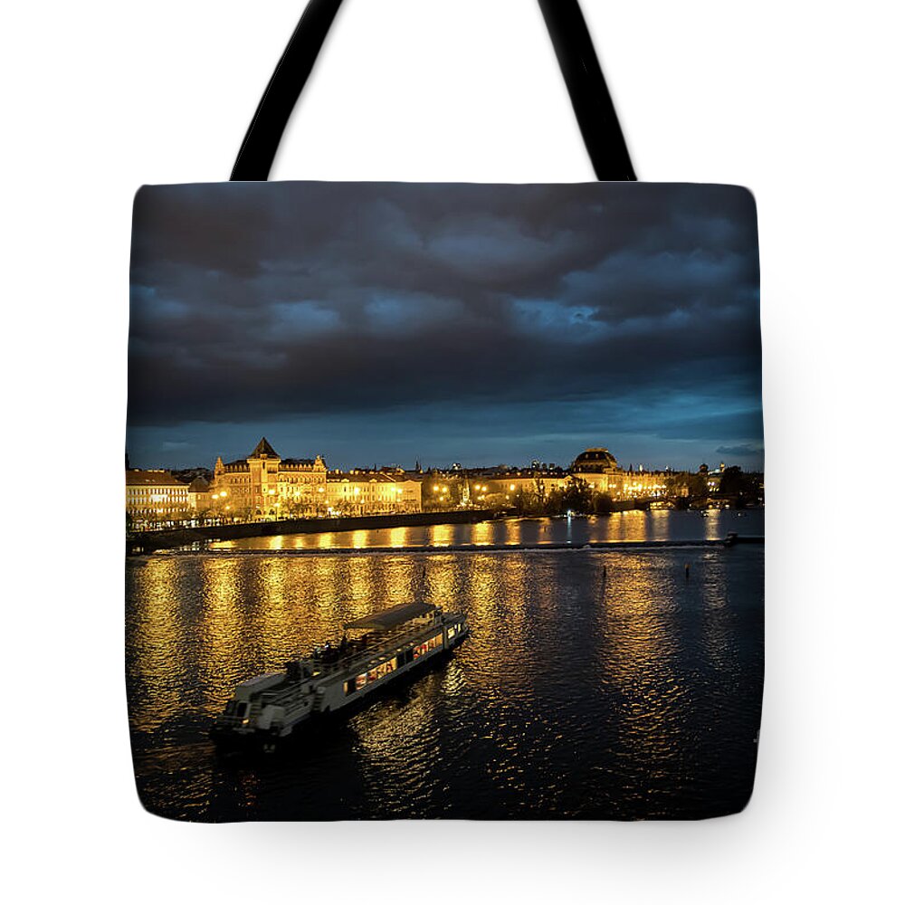 Architecture Tote Bag featuring the photograph Illuminated Moldova River With Ship And Buildings In The Night In Prague In The Czech Republic by Andreas Berthold