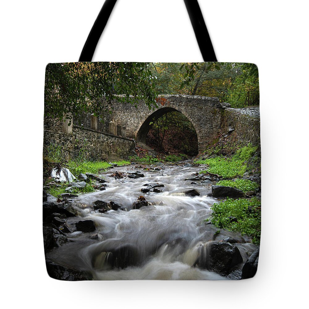 River Tote Bag featuring the photograph Medieval stoned bridge water flowing in the river. by Michalakis Ppalis