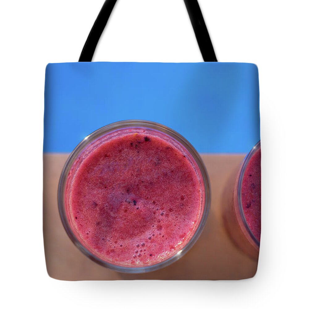 Drink Tote Bag featuring the photograph Pink fruit smoothies by the beautiful blue pool by Adriana Mueller