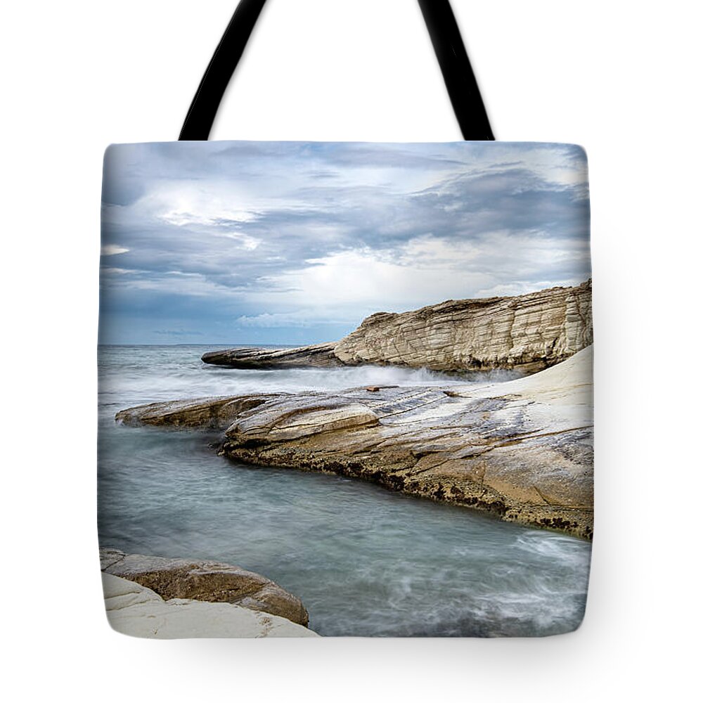 Seascape Tote Bag featuring the photograph Rocky seacoast and waves splashing on with white rocks by Michalakis Ppalis