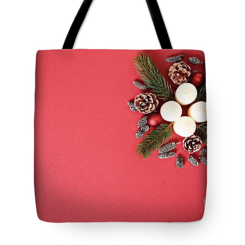 Seasonal Tote Bag featuring the photograph Seasonal greeting card concept with candles, pine cones and everg by Mendelex Photography
