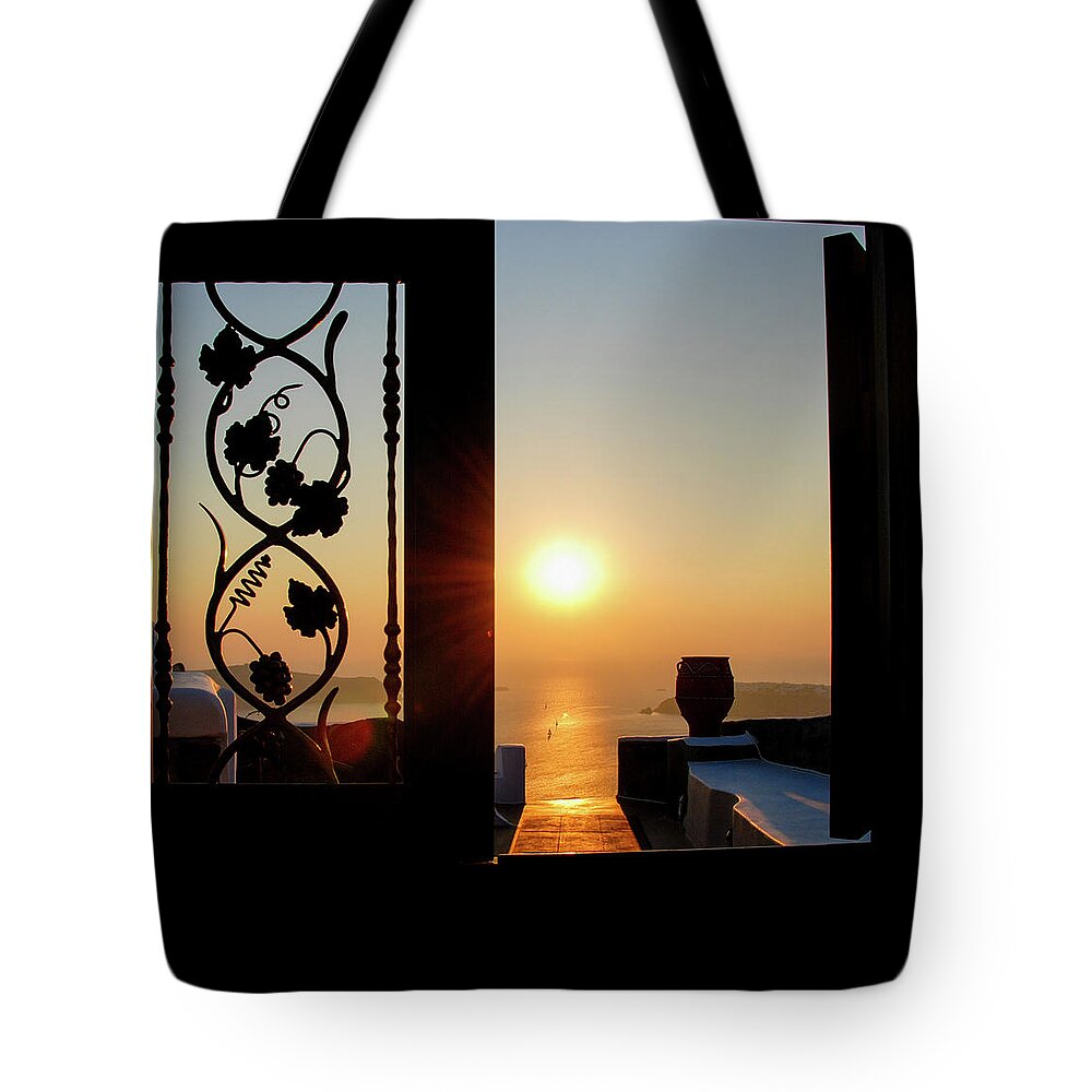 Nightfall Tote Bag featuring the photograph Sunset in the aegean sea from a house. Santorini island Greece. by Michalakis Ppalis