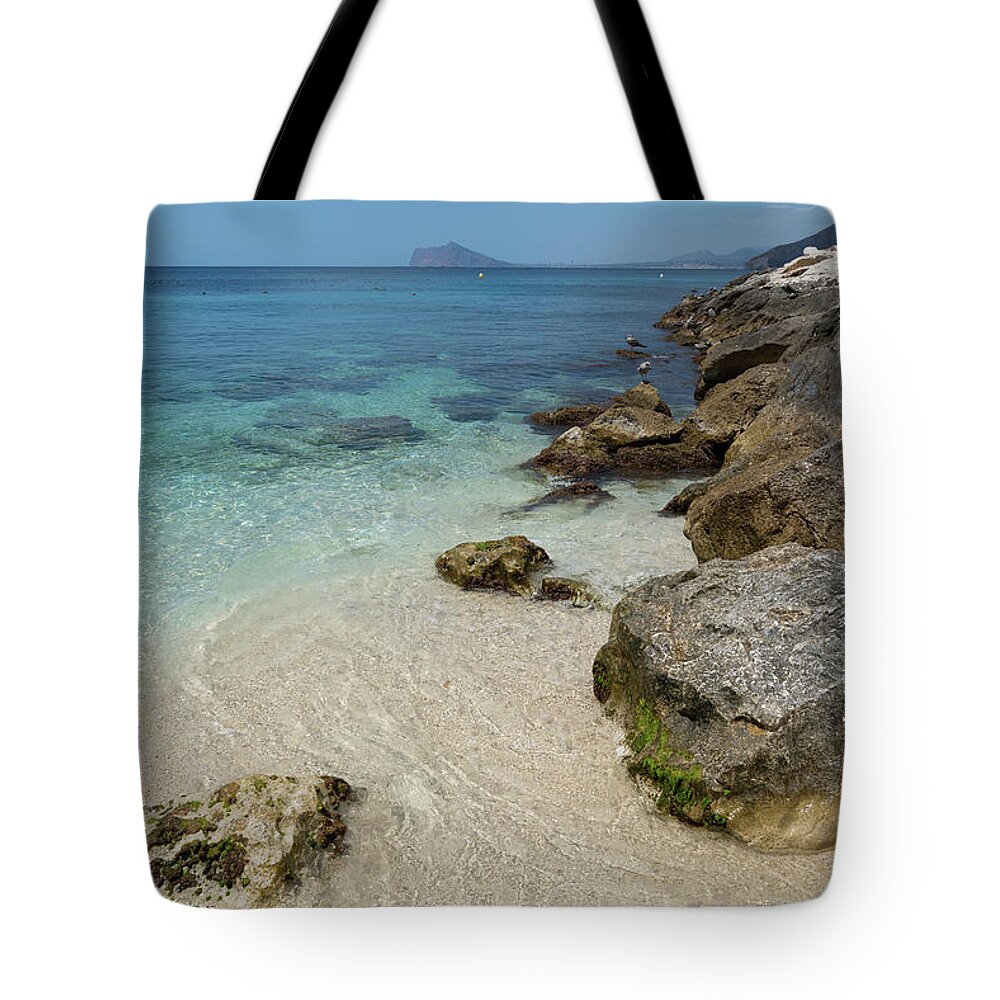 Mediterranean Tote Bag featuring the photograph Turquoise blue sea water and rocks in Calpe 1 by Adriana Mueller