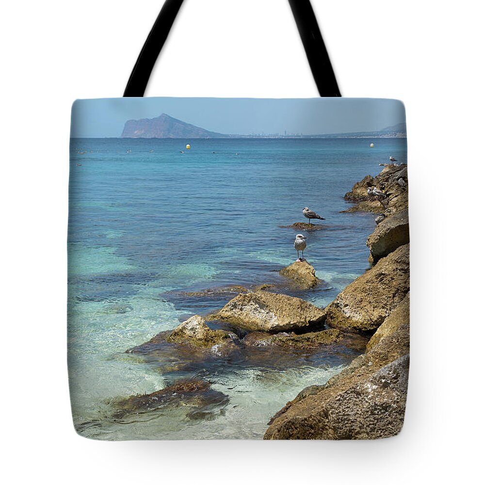 Mediterranean Tote Bag featuring the photograph Turquoise blue sea water and rocks in Calpe 2 by Adriana Mueller