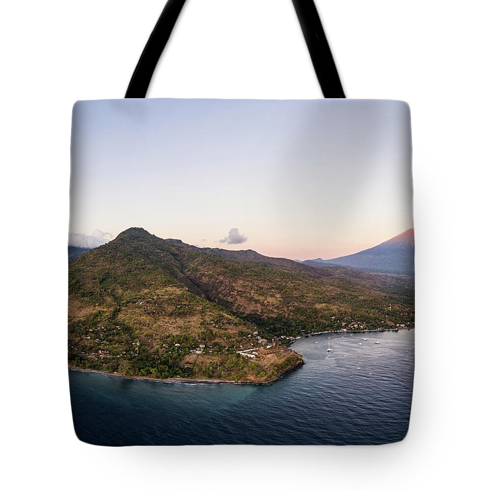 Amed Tote Bag featuring the photograph Twilight over the north Bali coast with the Agung volcano near A by Didier Marti