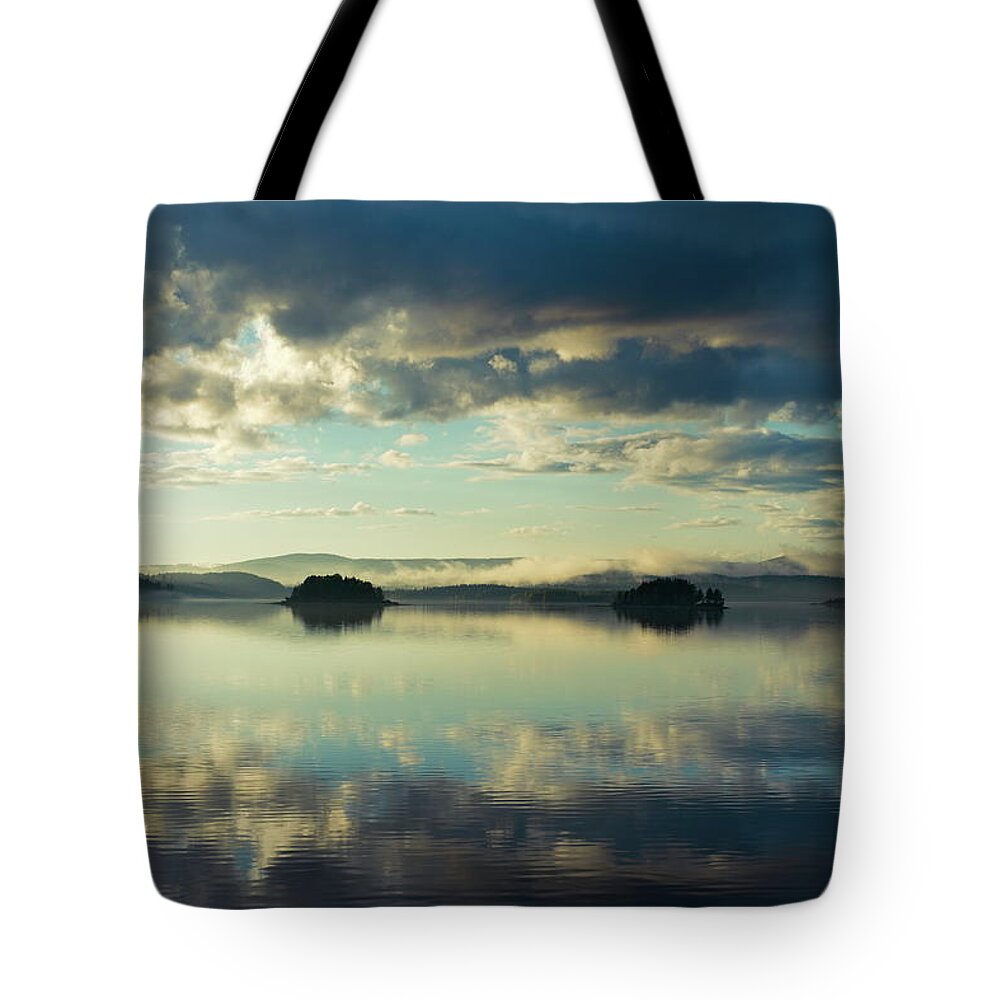 Autumn Tote Bag featuring the photograph Two islands and the cloudy sky are reflected in a glassy lake by Ulrich Kunst And Bettina Scheidulin