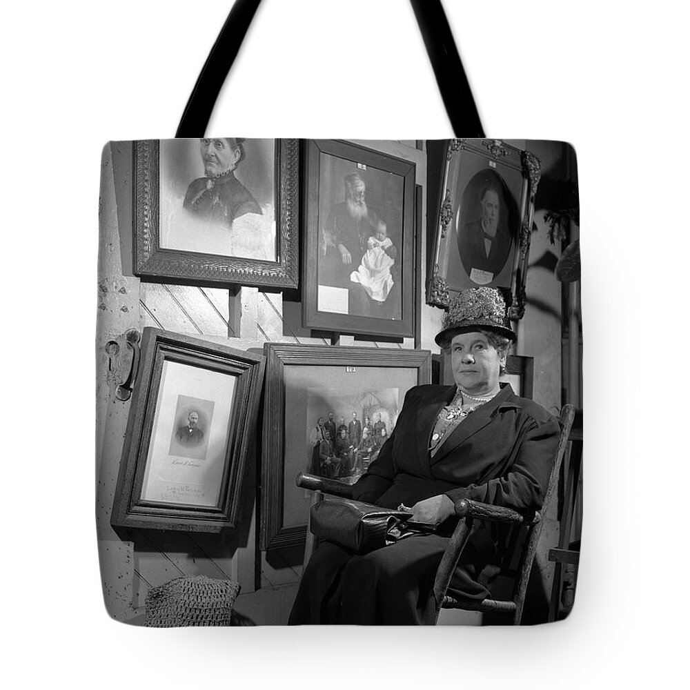 Genealogy Tote Bag featuring the photograph Woman seated in front of portraits of family members, 1946. by The Harrington Collection
