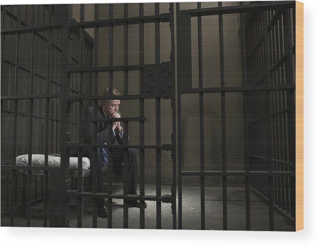 Corporate Business Wood Print featuring the photograph Mature businessman sitting on bed in prison cell #1 by Darrin Klimek