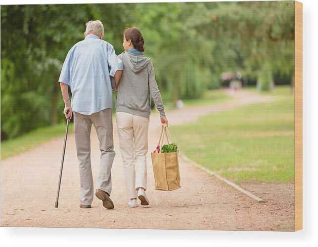 Mature Adult Wood Print featuring the photograph Caregiver – woman helping senior man with shopping by FredFroese