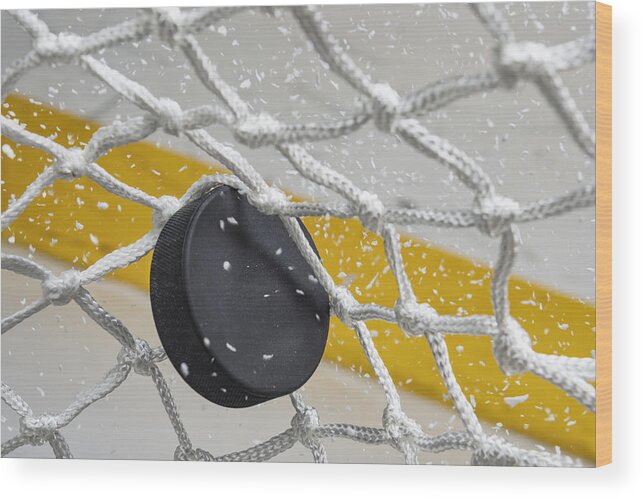 Goal Wood Print featuring the photograph Close-up of an Ice Hockey puck hitting the back of the net as snow flies, front view by Cmannphoto