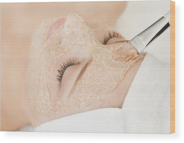 Tranquility Wood Print featuring the photograph Close up of woman's face with beauty mask being applied, Studio shot by Vstock