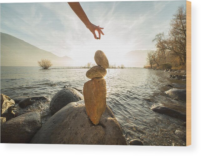 People Wood Print featuring the photograph Detail of person stacking rocks by the lake by Swissmediavision