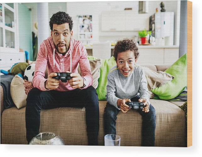 Three Quarter Length Wood Print featuring the photograph Father And Son Concentrating While Playing Video Games Together by Tom Werner