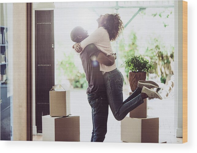 Young Men Wood Print featuring the photograph Happy man lifting woman in new house by Portra
