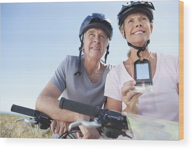 Heterosexual Couple Wood Print featuring the photograph Happy mature woman mountain biking with man using GPS by OJO Images