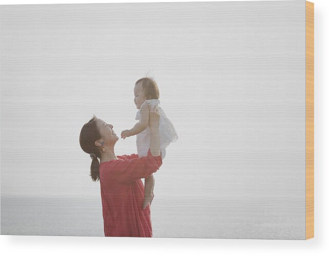 Tranquility Wood Print featuring the photograph Mother and baby girl relaxed at seaside by Kohei_hara