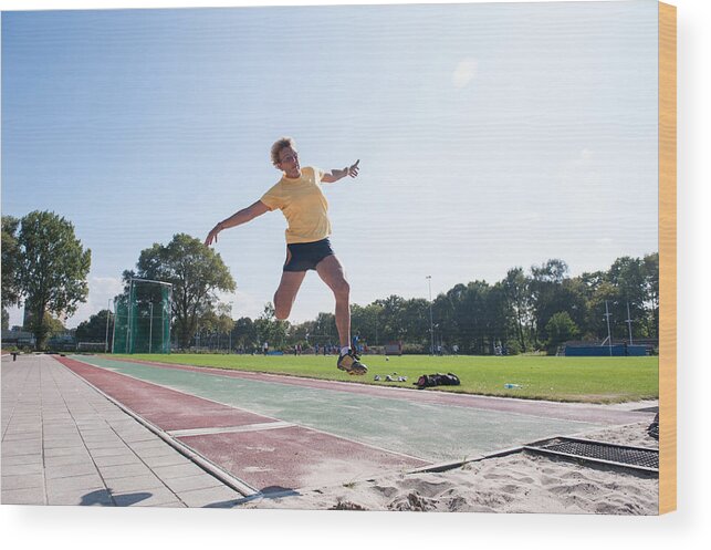 North Holland Wood Print featuring the photograph Senior athlete (75) practicing long jump by Lucy Lambriex