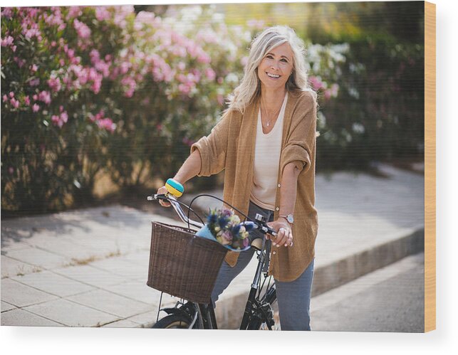 Mature Adult Wood Print featuring the photograph Smiling senior woman having fun riding vintage bike in spring by Wundervisuals