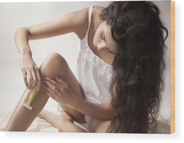 Three Quarter Length Wood Print featuring the photograph Young woman shaving legs by PhotoAlto/Jana Hernette