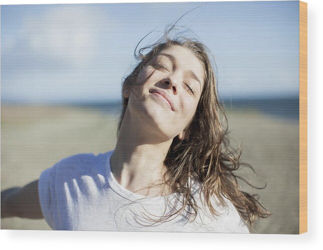 People Wood Print featuring the photograph Young woman with eyes closed smiling on a beach by Letizia McCall