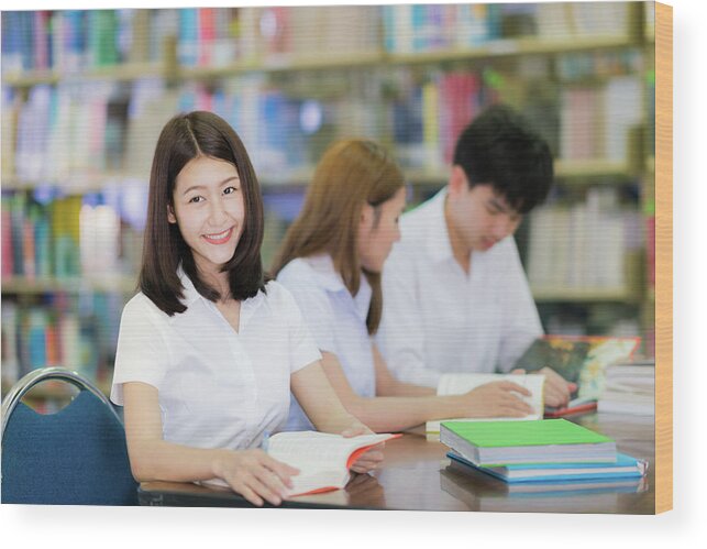 College Wood Print featuring the photograph Asian student lady smile and read a book in library in universit by Anek Suwannaphoom