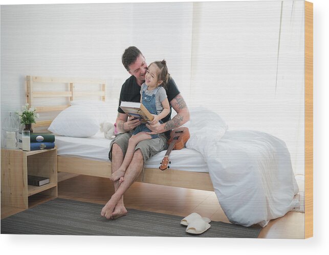 Father Wood Print featuring the photograph Father and daugther play and read a book in bedroom by Anek Suwannaphoom