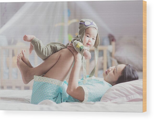 Baby Wood Print featuring the photograph Mother play with her baby after walkup on the bed in bedroom by Anek Suwannaphoom