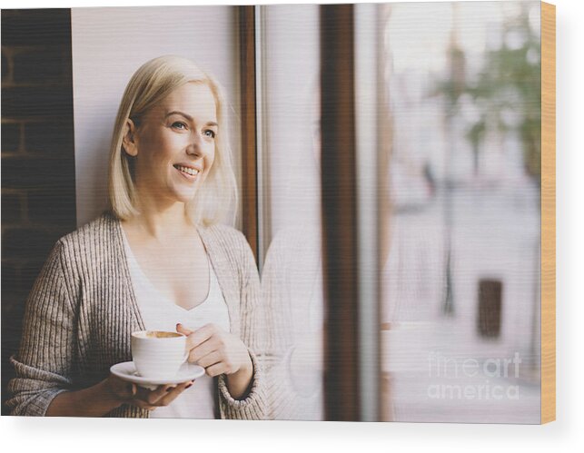Woman Wood Print featuring the photograph Woman with a cup of coffee standing by the window. by Michal Bednarek