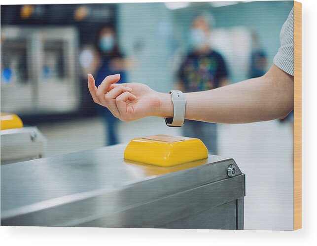 Subway Wood Print featuring the photograph Cropped shot of young Asian woman checking in at subway station using contactless payment for subway ticket via smartwatch #1 by D3sign