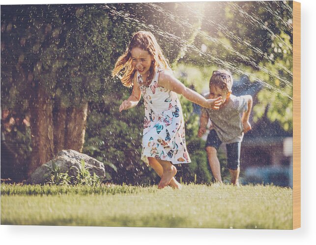 Grass Wood Print featuring the photograph Happy kids playing with garden sprinkler #1 by Lisegagne